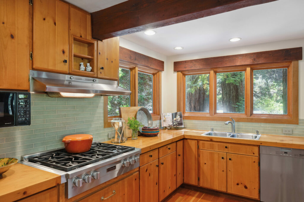 A cool green tile backsplash contrasts with the warmth of the pine cabinets and countertops. (Open Homes Photography)