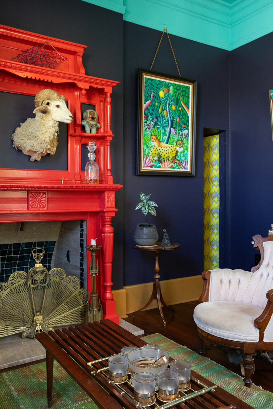 The couple’s formal front parlor, with vivid colors, vintage furniture and artwork from the Haitian painter Fritz Merise. (Eileen Roche)