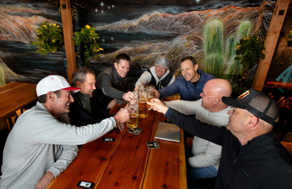 Randall Behrens, front left, of Windsor, with Aaron Carpenter of Healdsburg, front right, toast with friends at Cooperage Brewing’s new location in downtown Santa Rosa, Friday, December 20, 2024. (Darryl Bush / For The Press Democrat)