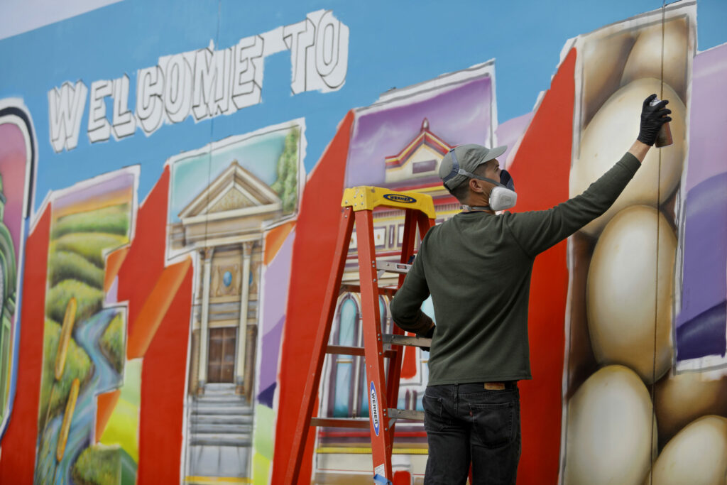 Mural artist Maxfield Bala applies spray paint to his "Welcome to Petaluma" mural project on Petaluma Blvd South along Highway 101 in Petaluma on Monday, January 28, 2019. (Beth Schlanker / The Press Democrat)