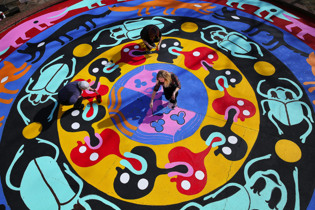 An artist who goes by the pseudonym Bud Snow, lower right, paints her mandala mural with the help of Judy Kennedy, left, and Reina Rivera at Juilliard Park in Santa Rosa, on Wednesday, February 10, 2016. The mural was commissioned by the Santa Rosa Art in Public Places Committee with a grant from Downtown Connect. (Christopher Chung/ The Press Democrat)