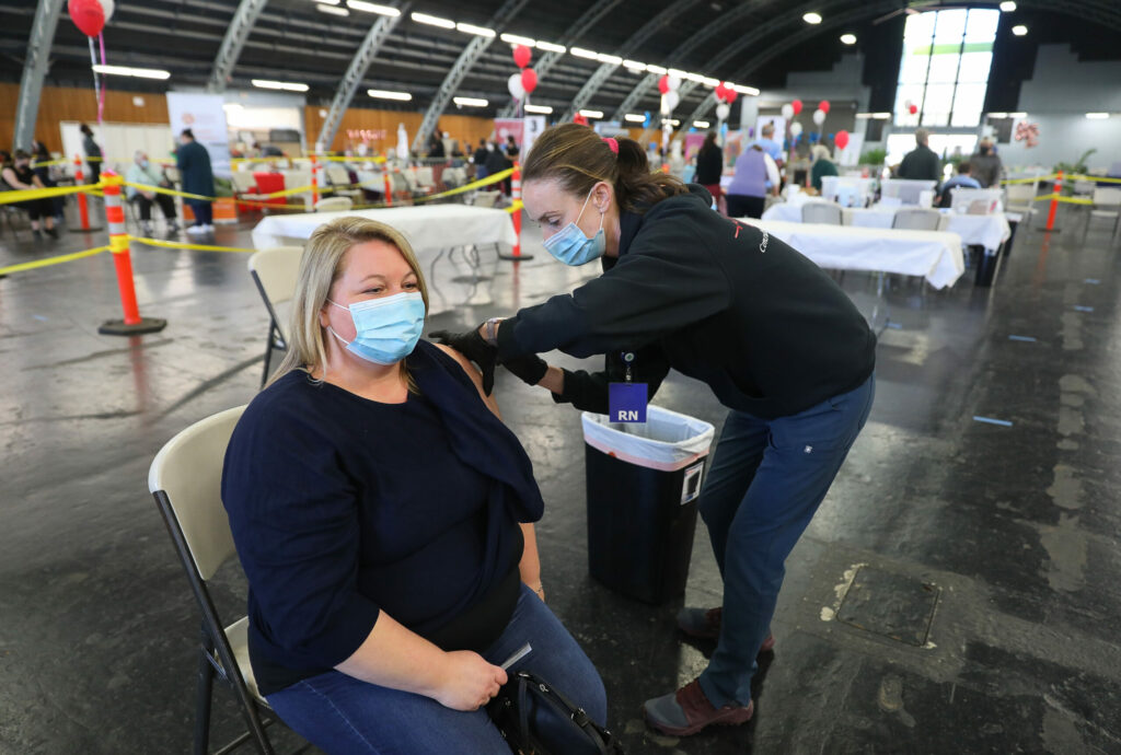 Registered nurse Lilly Briggs, right, administers the Moderna COVID-19 vaccine to Sabrina Nesbit at the DEMA, Disaster Emergency Medical Assistance, vaccination clinic, at the Sonoma County Fairgrounds, in Santa Rosa on Monday, February 22, 2021. (Christopher Chung/ The Press Democrat)