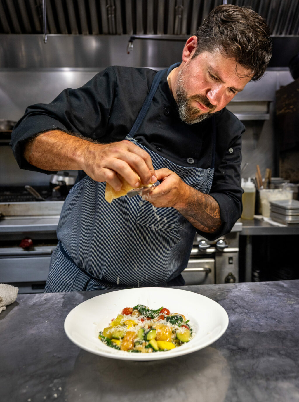 Grata Italian Eatery chef/owner Eric Foster tops his Spring Harvest Gnudi with grated cheese Thursday, May 8, 2025, in Windsor. (John Burgess / The Press Democrat)