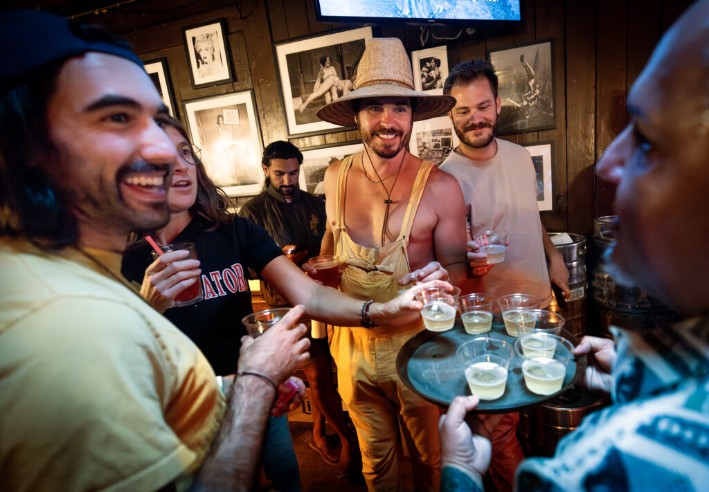Auctioneer Nick Schwanz, center in hat, and his friends grab Champagne to celebrate raising more than  million for local charities over the past 20 years on Give Back Tuesdays, June 24, 2025, at the Rainbow Cattle Co. in Guerneville. (John Burgess / Press Democrat)