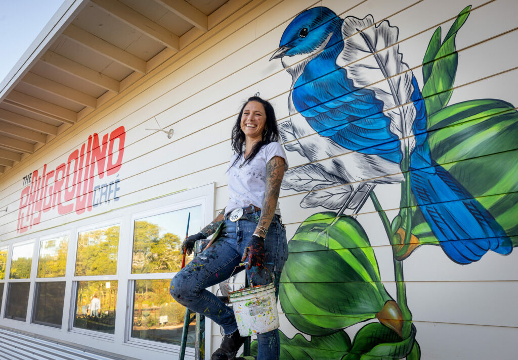 Muralist Amanda Lynn puts the final touches of color on a bluebird on a fig tree on the outer walls of The Playground Café at St. Stephen's Church Wednesday, Oct. 16, 2024, in Sebastopol. (John Burgess / The Press Democrat)