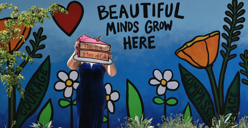 The Velvet Bandit with a mural she painted on the grounds of Anova Center for Education in Santa Rosa, Wednesday, July 2, 2025. (Kent Porter / The Press Democrat)