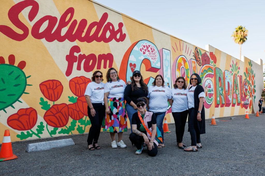 Staff of La Familia Sana from left to right; Laura Arreguin, Jade Weymouth, Andrea G, Christina Rosas, Maria De Jesus Ferreira, Mayra Arreguin and Blanca Molina (center), muralist, stand in front of Molina’s mural during its unveiling in Cloverdale on Sept. 20, 2024. (Abraham Fuentes/For The Press Democrat)
