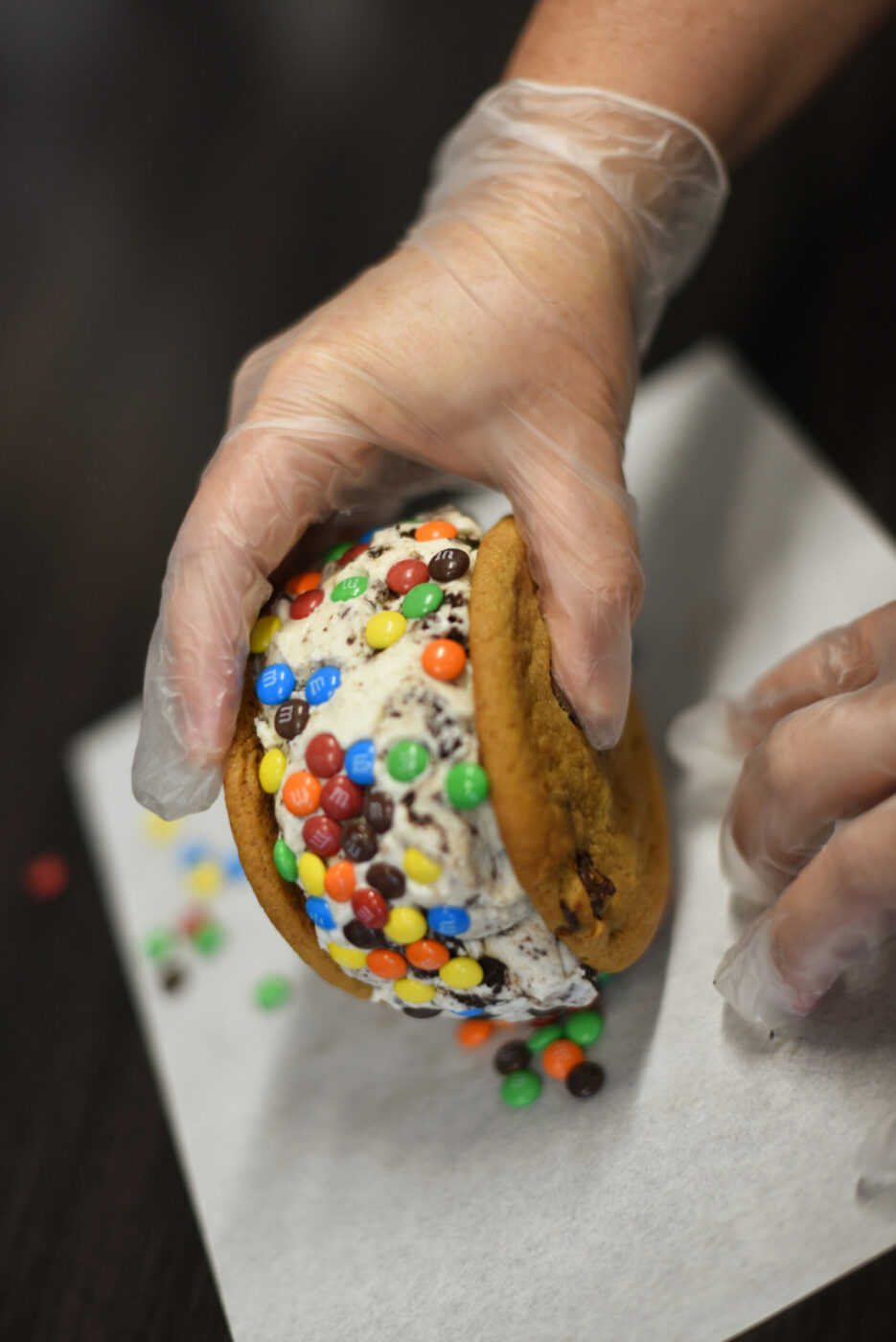 Co-owner Linsee Sage rolls cookies and cream ice cream on mini M&M's at Squatch's Gourmet Ice Cream Sandwiches and Coffee in Rohnert Park on Saturday, July 10, 2021. (Erik Castro/for The Press Democrat)